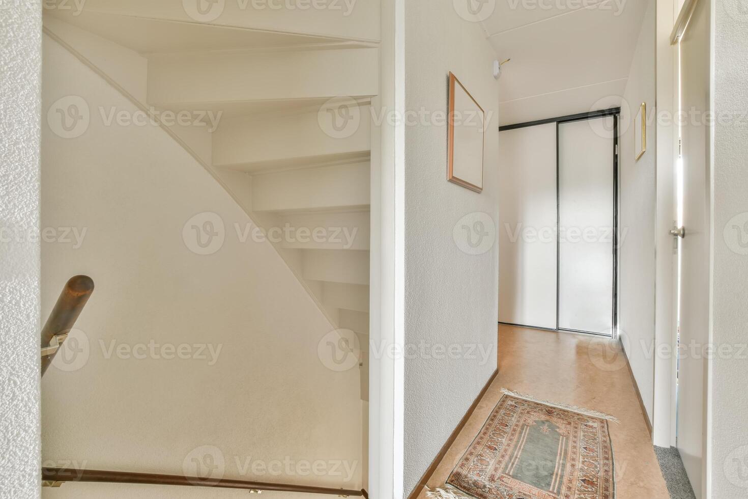 A hallway with a white door and stairs photo
