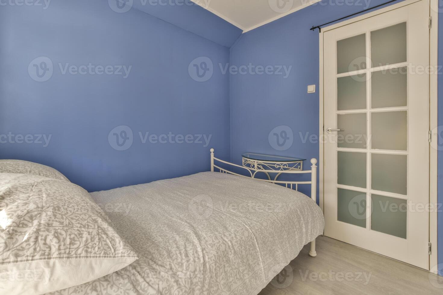 A bedroom with blue walls and a white bed photo