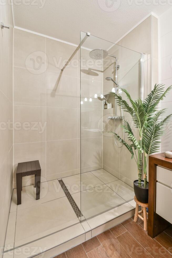 A bathroom with a glass shower door and a wooden bench photo