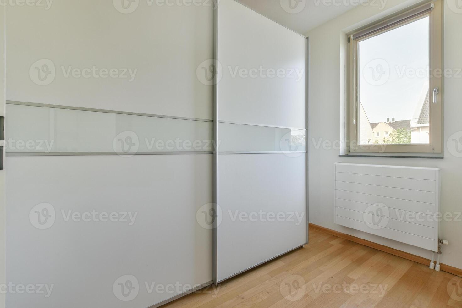 A white closet with sliding doors and a window photo