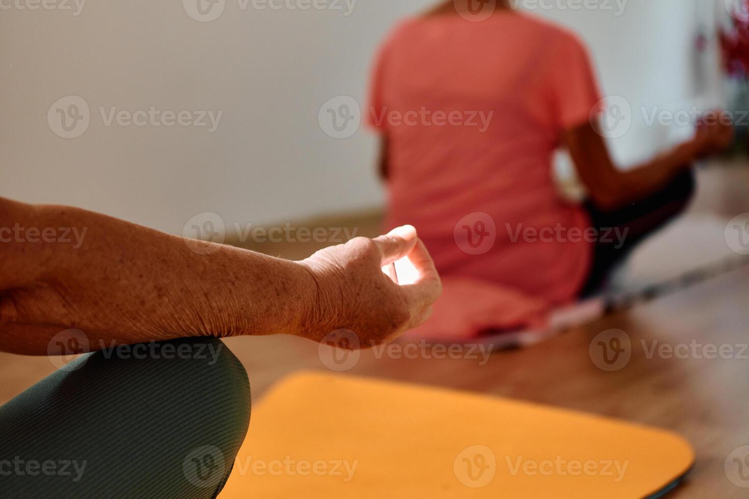 In this sunlit space, a senior woman's hand gracefully engages in various yoga poses, embodying the essence of active aging, health, and inner peace photo