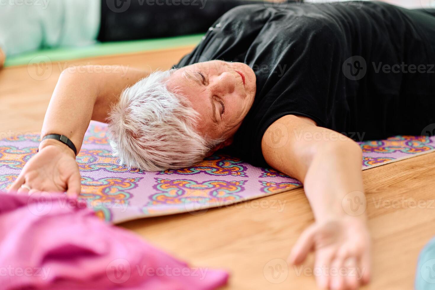 In a sunlit space, a senior woman gracefully practices rejuvenating yoga, focusing on neck, back, and leg stretches, embodying serenity and well-being photo