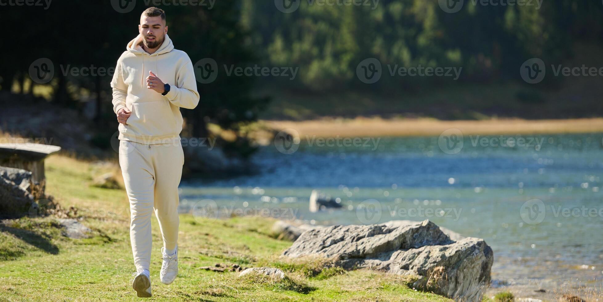 Athletic man maintains his healthy lifestyle by running through the scenic mountain and lakeside environment, showcasing a commitment to fitness and well-being photo