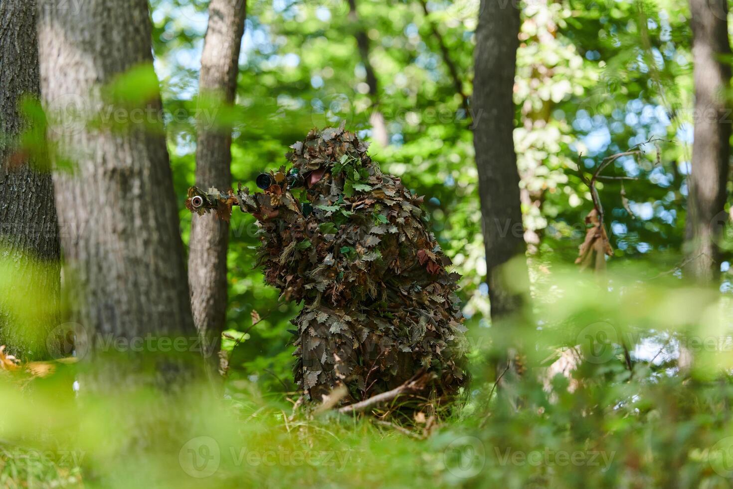 A highly skilled elite sniper, camouflaged in the dense forest, stealthily maneuvers through dangerous woodland terrain on a covert and precise mission photo