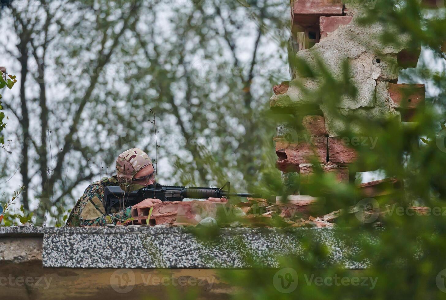 An elite soldier, camouflaged and stealthily navigating through dangerous woodland terrain, executes a covert mission in a secluded forest area photo