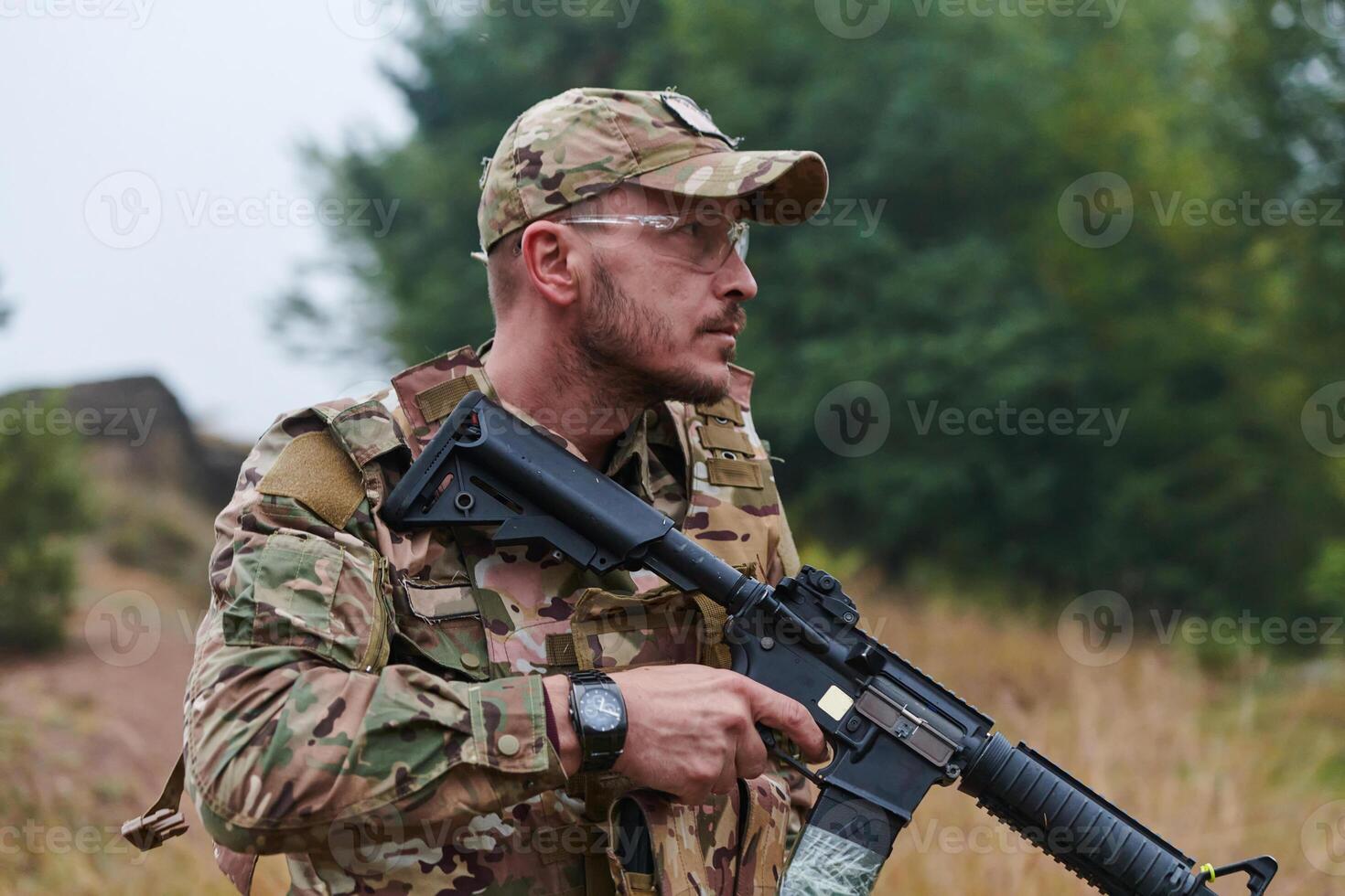 An elite soldier, camouflaged and stealthily navigating through dangerous woodland terrain, executes a covert mission in a secluded forest area photo
