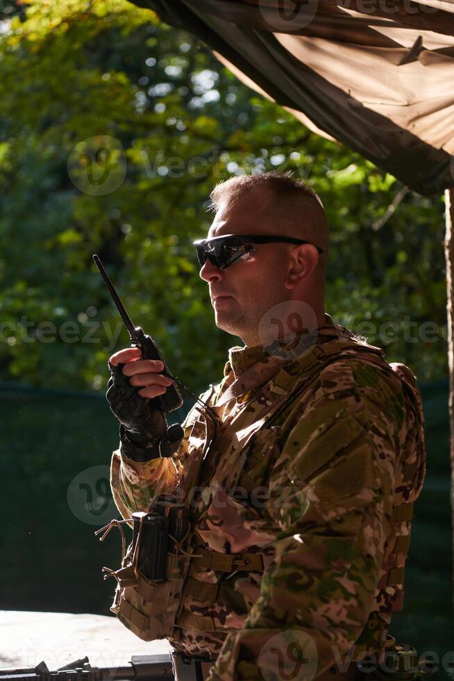 A military major employs a Motorola radio for seamless communication with his fellow soldiers during a tactical operation, showcasing professionalism and strategic coordination photo