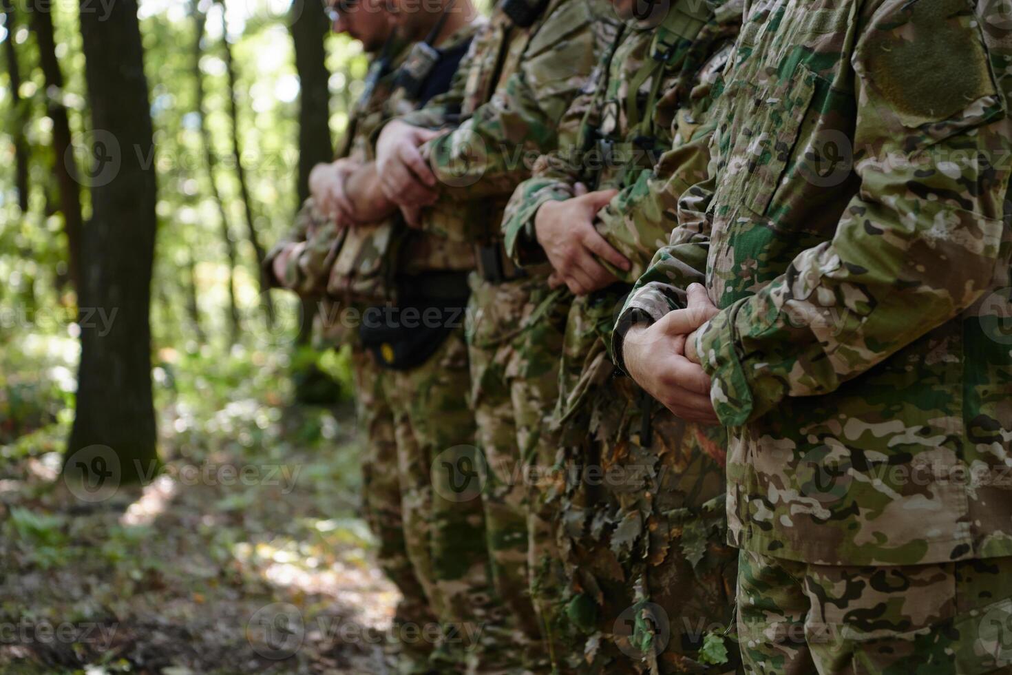 A dedicated group of soldiers engages in Islamic prayer amidst the challenging and perilous conditions of a military operation in dense forested areas photo