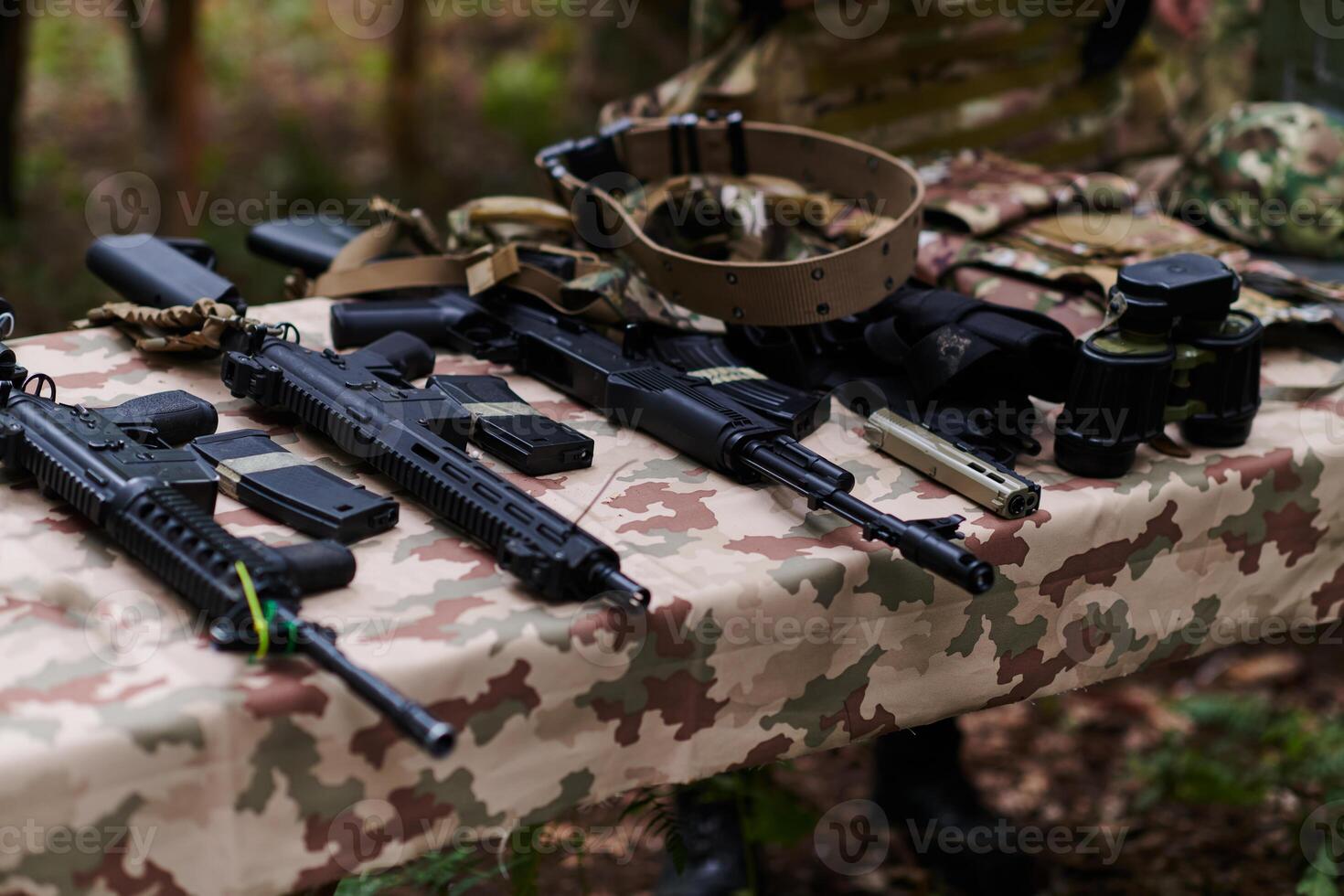 An array of military weapons, including rifles and pistols, is meticulously arranged on a table in a military base, presenting a close-up view of the diverse firepower and armament meticulously photo