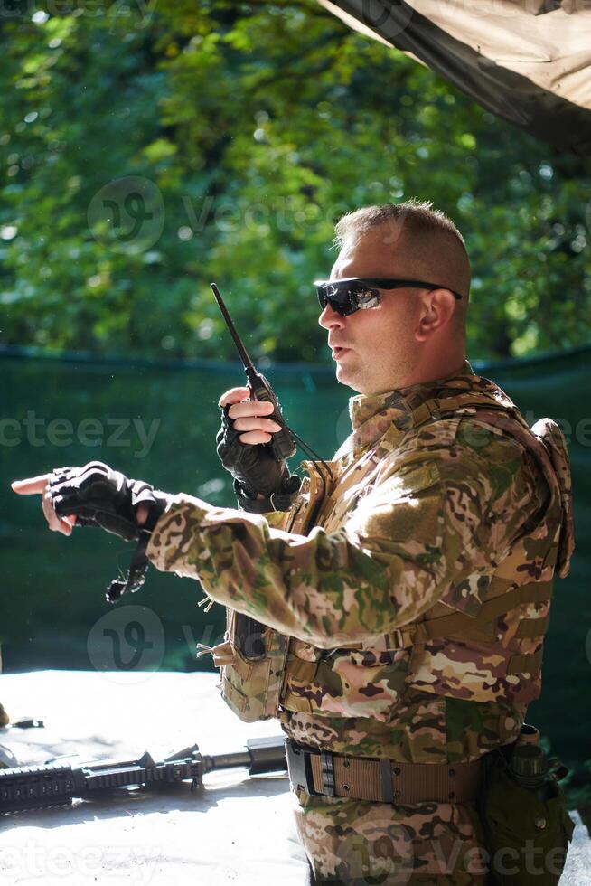 A military major employs a Motorola radio for seamless communication with his fellow soldiers during a tactical operation, showcasing professionalism and strategic coordination photo