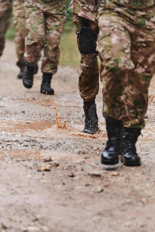 Close up photo, the resilient legs of elite soldiers, clad in camouflage boots, stride purposefully along a hazardous forest path as they embark on a high-stakes military mission photo