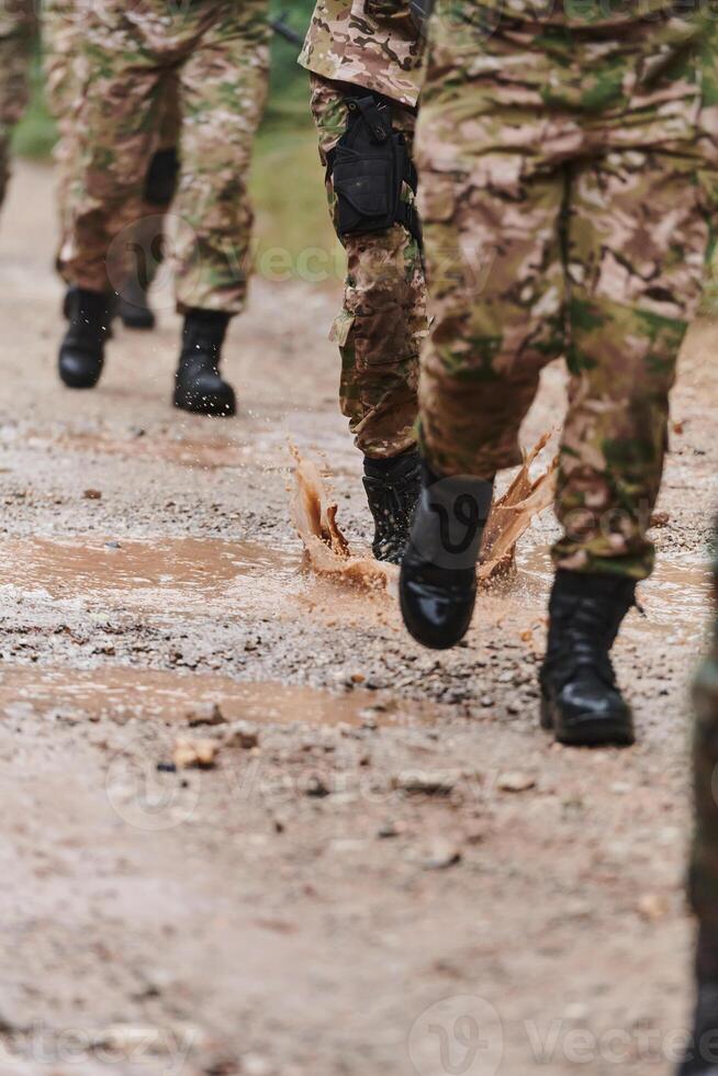 Close up photo, the resilient legs of elite soldiers, clad in camouflage boots, stride purposefully along a hazardous forest path as they embark on a high-stakes military mission photo