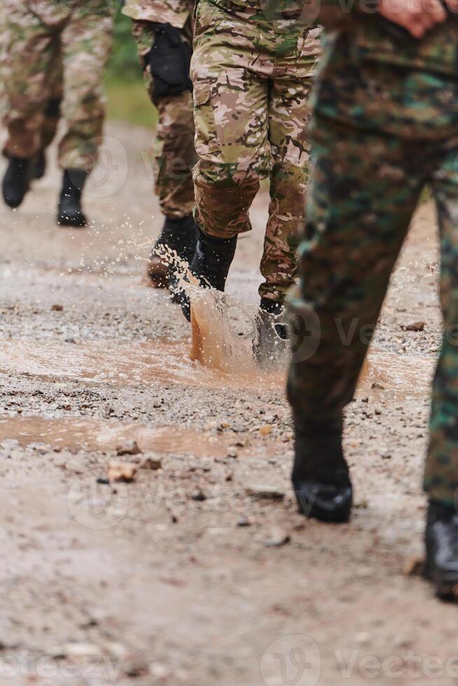 Close up photo, the resilient legs of elite soldiers, clad in camouflage boots, stride purposefully along a hazardous forest path as they embark on a high-stakes military mission photo