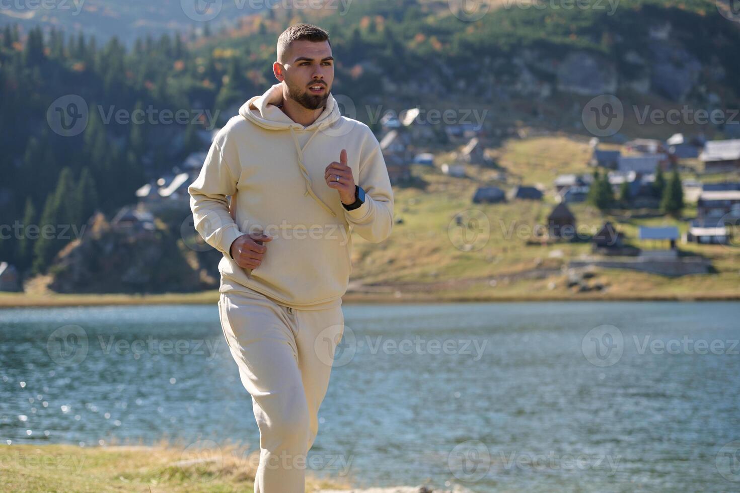 Athletic man maintains his healthy lifestyle by running through the scenic mountain and lakeside environment, showcasing a commitment to fitness and well-being photo
