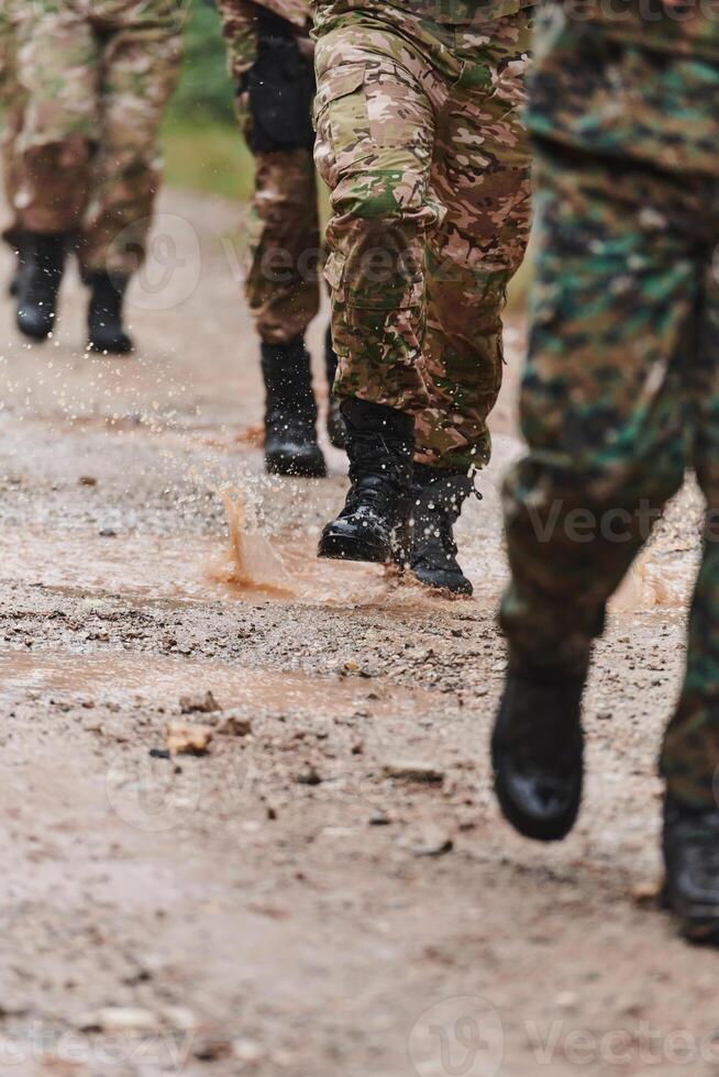 Close up photo, the resilient legs of elite soldiers, clad in camouflage boots, stride purposefully along a hazardous forest path as they embark on a high-stakes military mission photo