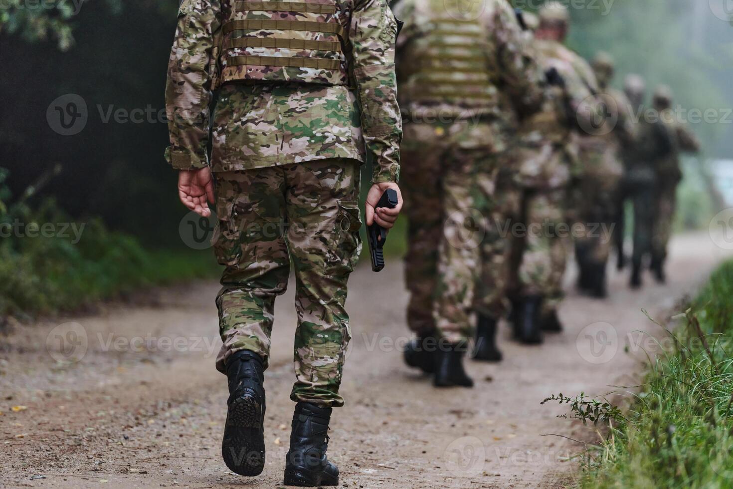 Close up photo, the resilient legs of elite soldiers, clad in camouflage boots, stride purposefully along a hazardous forest path as they embark on a high-stakes military mission photo