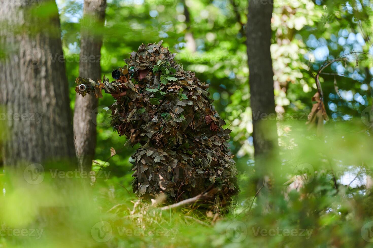A highly skilled elite sniper, camouflaged in the dense forest, stealthily maneuvers through dangerous woodland terrain on a covert and precise mission photo