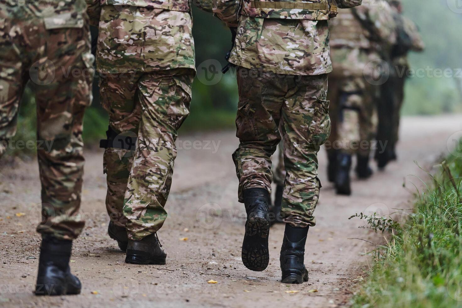 Close up photo, the resilient legs of elite soldiers, clad in camouflage boots, stride purposefully along a hazardous forest path as they embark on a high-stakes military mission photo