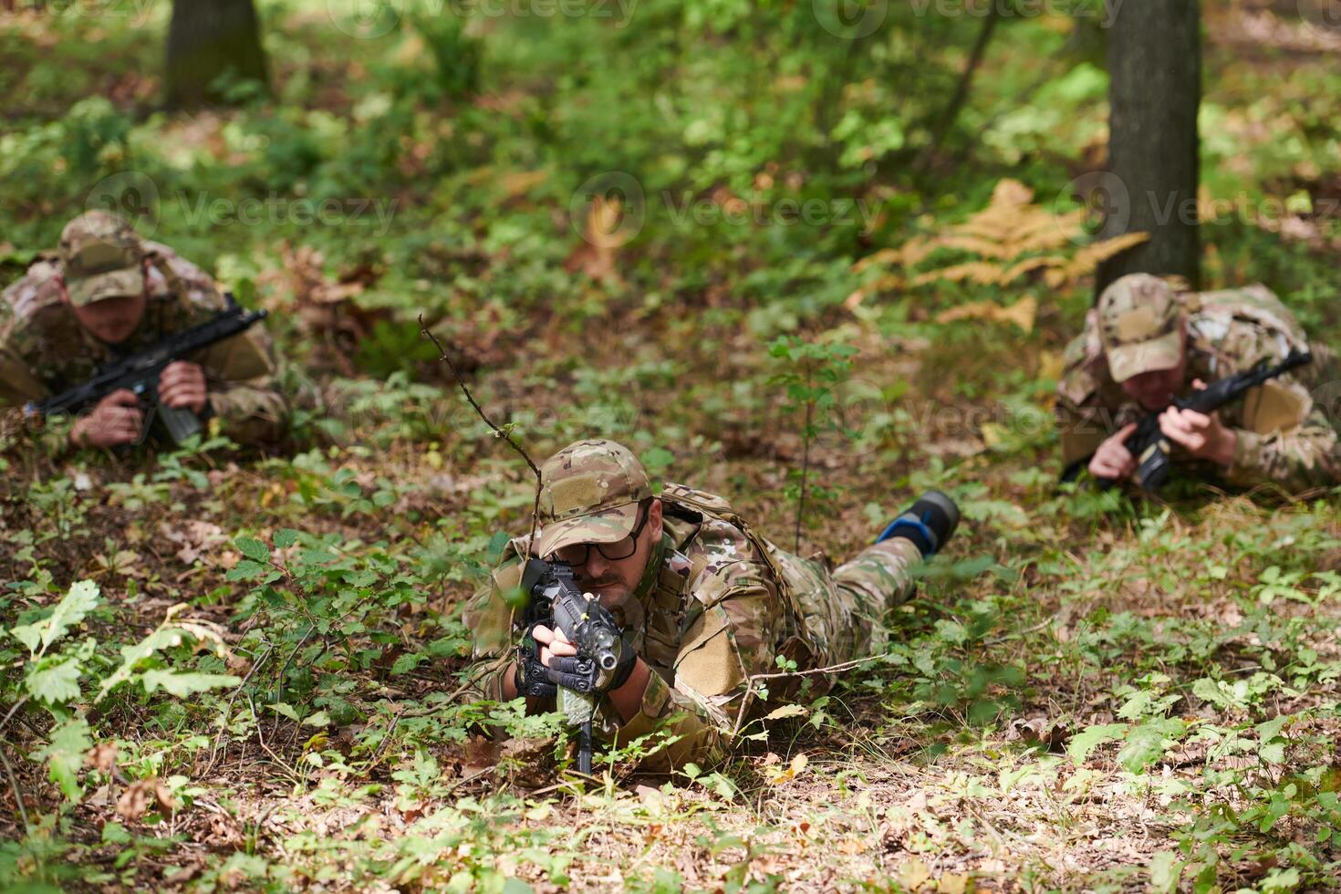 Elite soldiers stealthily maneuver through the dense forest, camouflaged in specialized gear, as they embark on a covert and strategic military mission photo