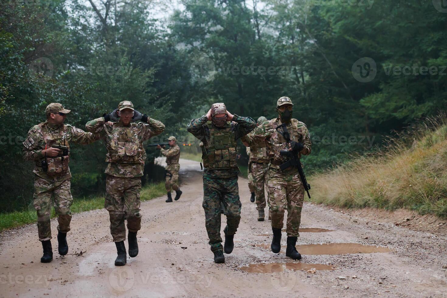 A group of elite soldiers leads captives through a military camp, showcasing a tense atmosphere of detention and security operations photo