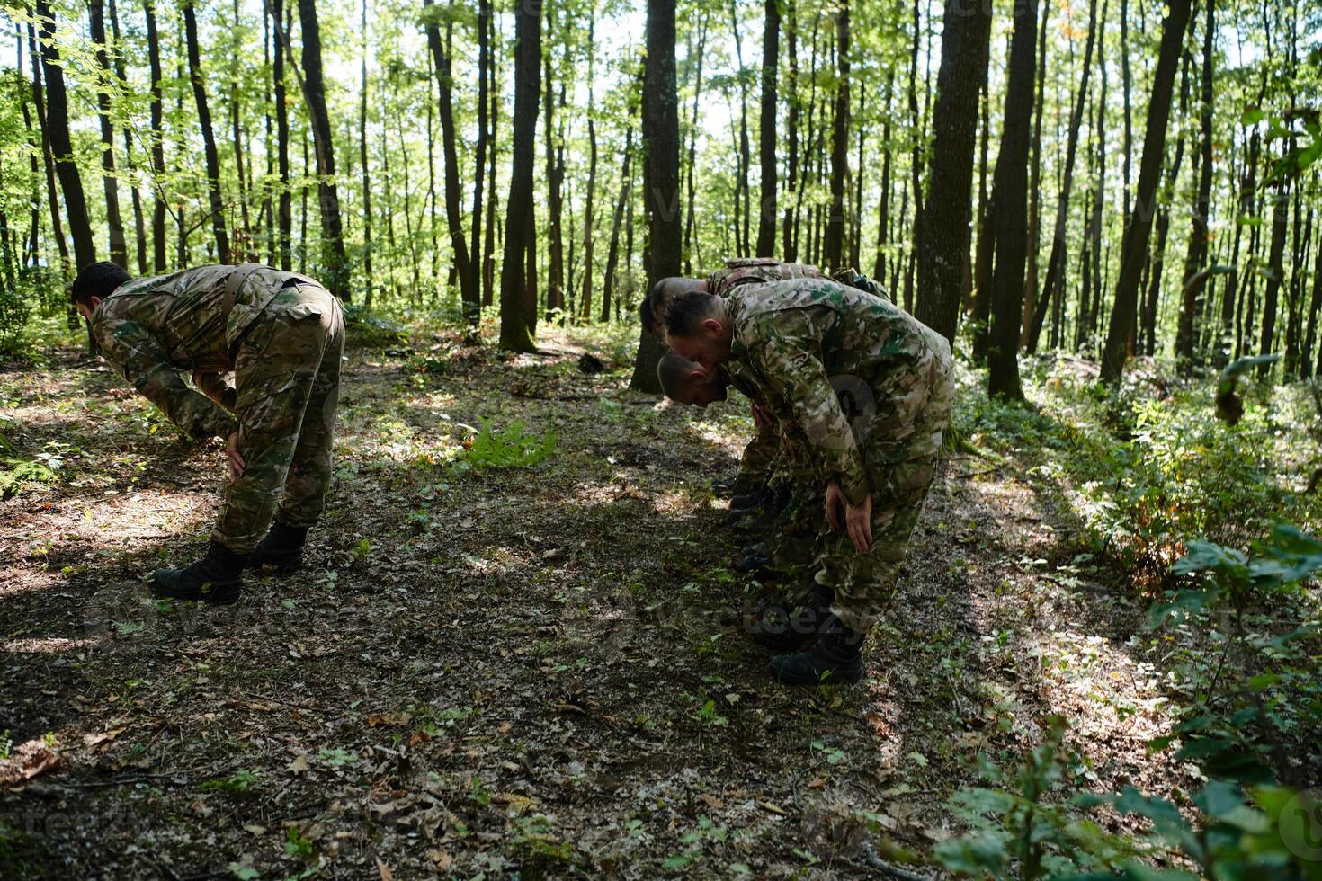A dedicated group of soldiers engages in Islamic prayer amidst the challenging and perilous conditions of a military operation in dense forested areas photo