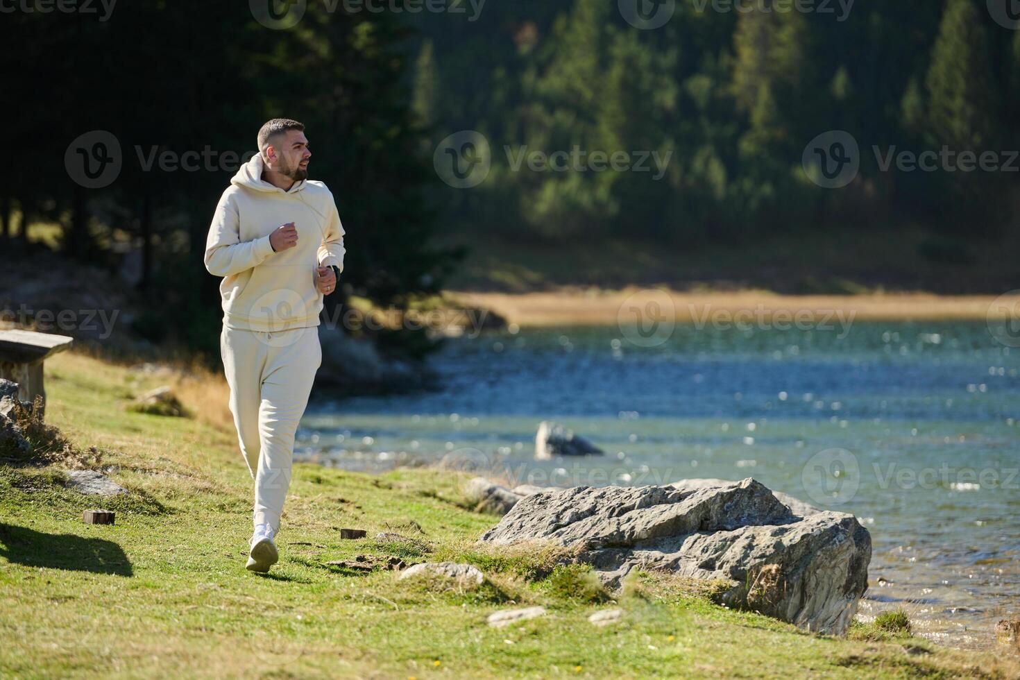 Athletic man maintains his healthy lifestyle by running through the scenic mountain and lakeside environment, showcasing a commitment to fitness and well-being photo