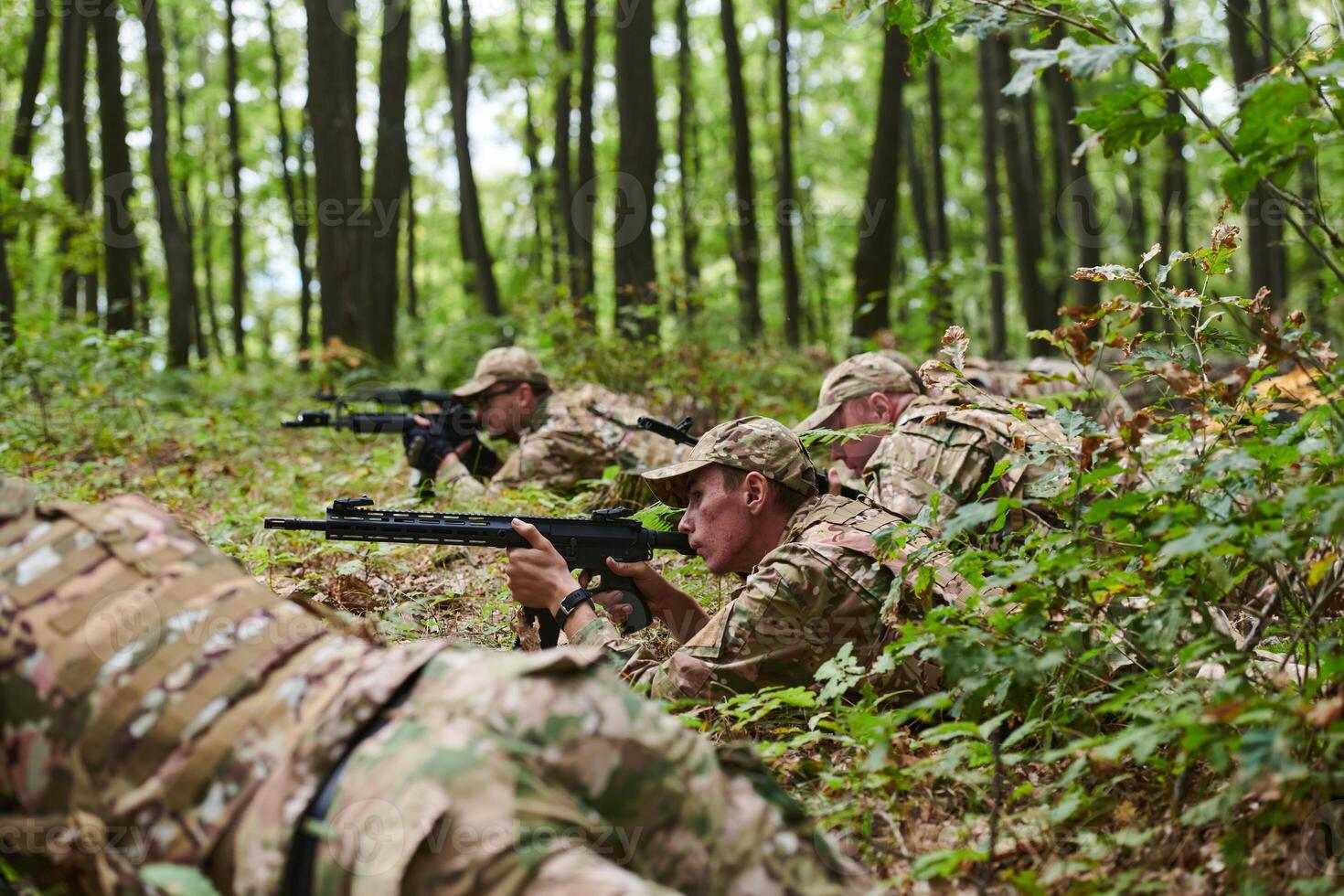 Elite soldiers stealthily maneuver through the dense forest, camouflaged in specialized gear, as they embark on a covert and strategic military mission photo