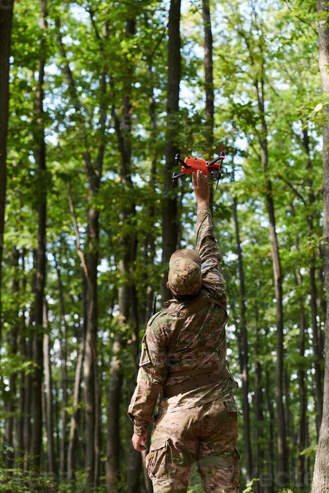 Elite military unit, equipped with state-of-the-art technology including a drone, strategically navigates and surveys dangerous wooded terrain, showcasing their precision, cooperation, and specialized photo