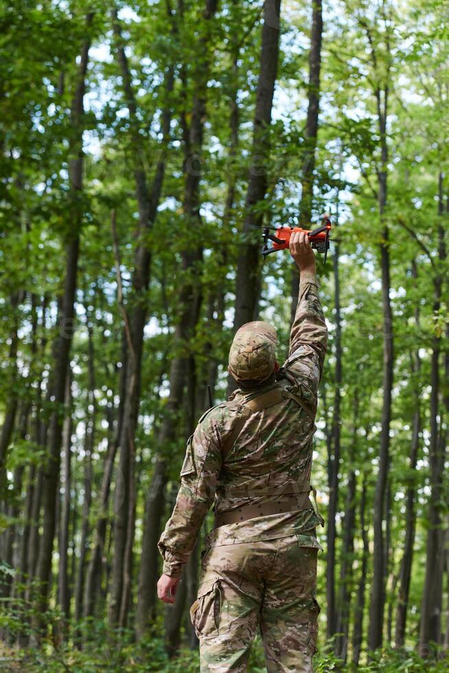 Elite military unit, equipped with state-of-the-art technology including a drone, strategically navigates and surveys dangerous wooded terrain, showcasing their precision, cooperation, and specialized photo
