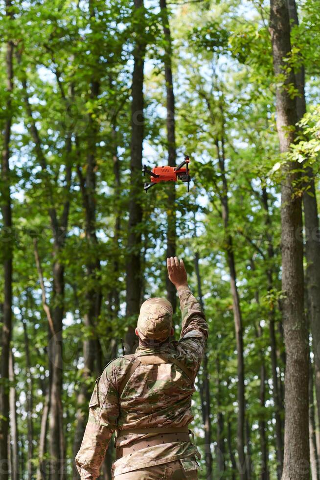 Elite military unit, equipped with state-of-the-art technology including a drone, strategically navigates and surveys dangerous wooded terrain, showcasing their precision, cooperation, and specialized photo