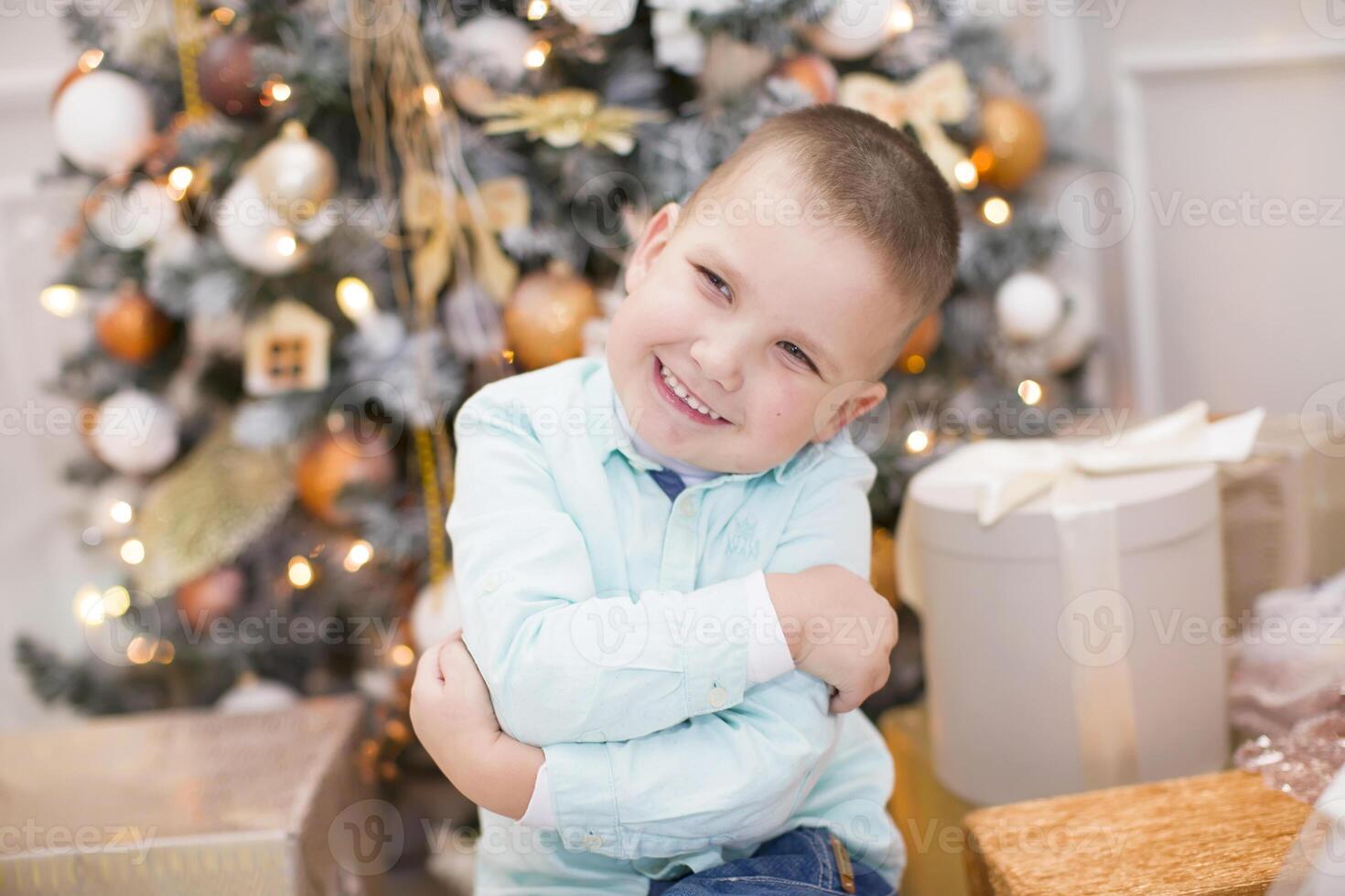 Joyful cheerful child at the New Year tree. The boy smiles on the background of the Christmas interior. photo