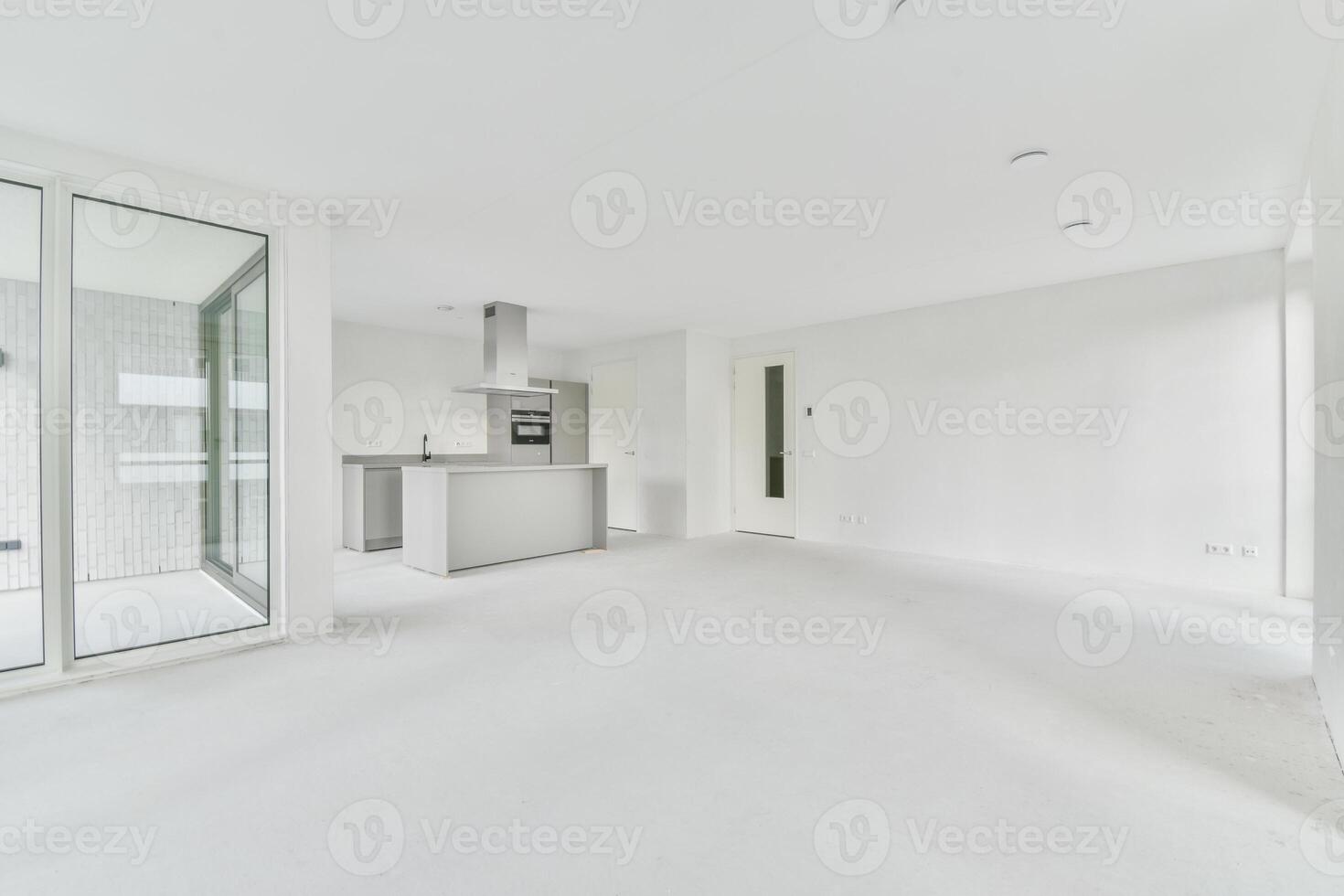 An empty white room with a kitchen and sliding glass doors photo