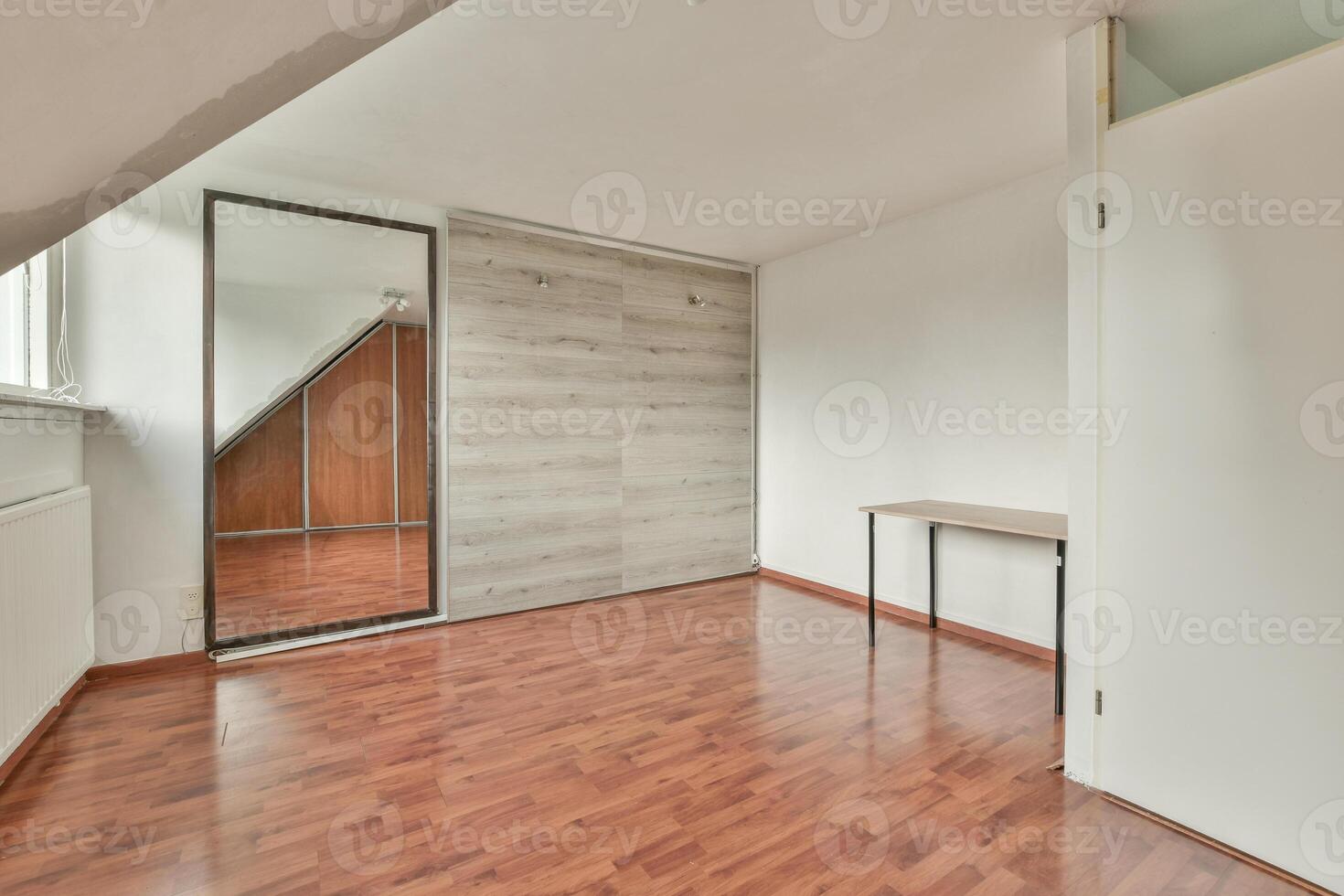 An empty room with wooden floors and a mirror photo