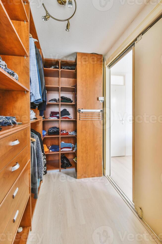 A walk in closet with clothes and shoes photo