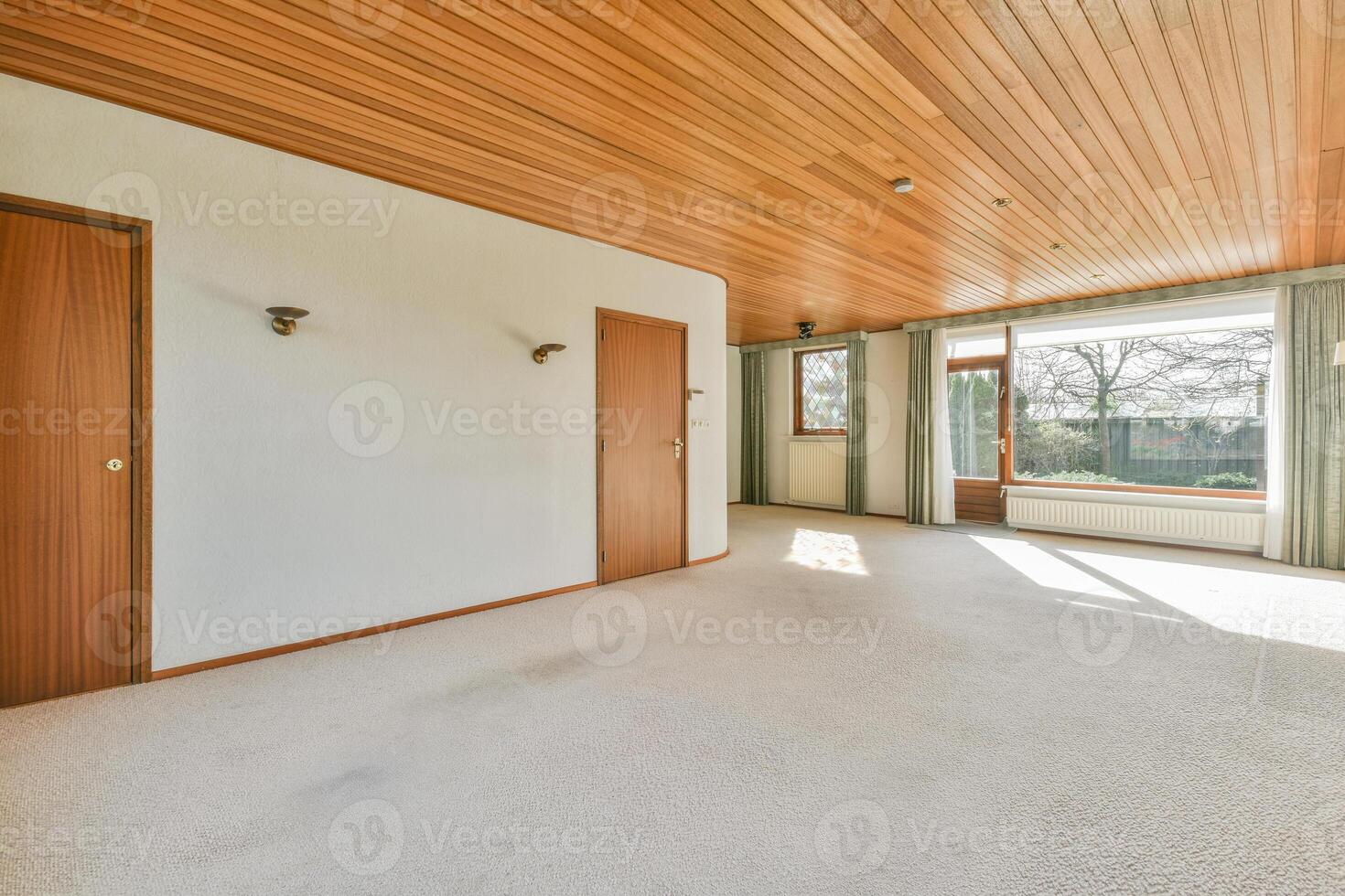 A large empty room with wood paneling and a window photo