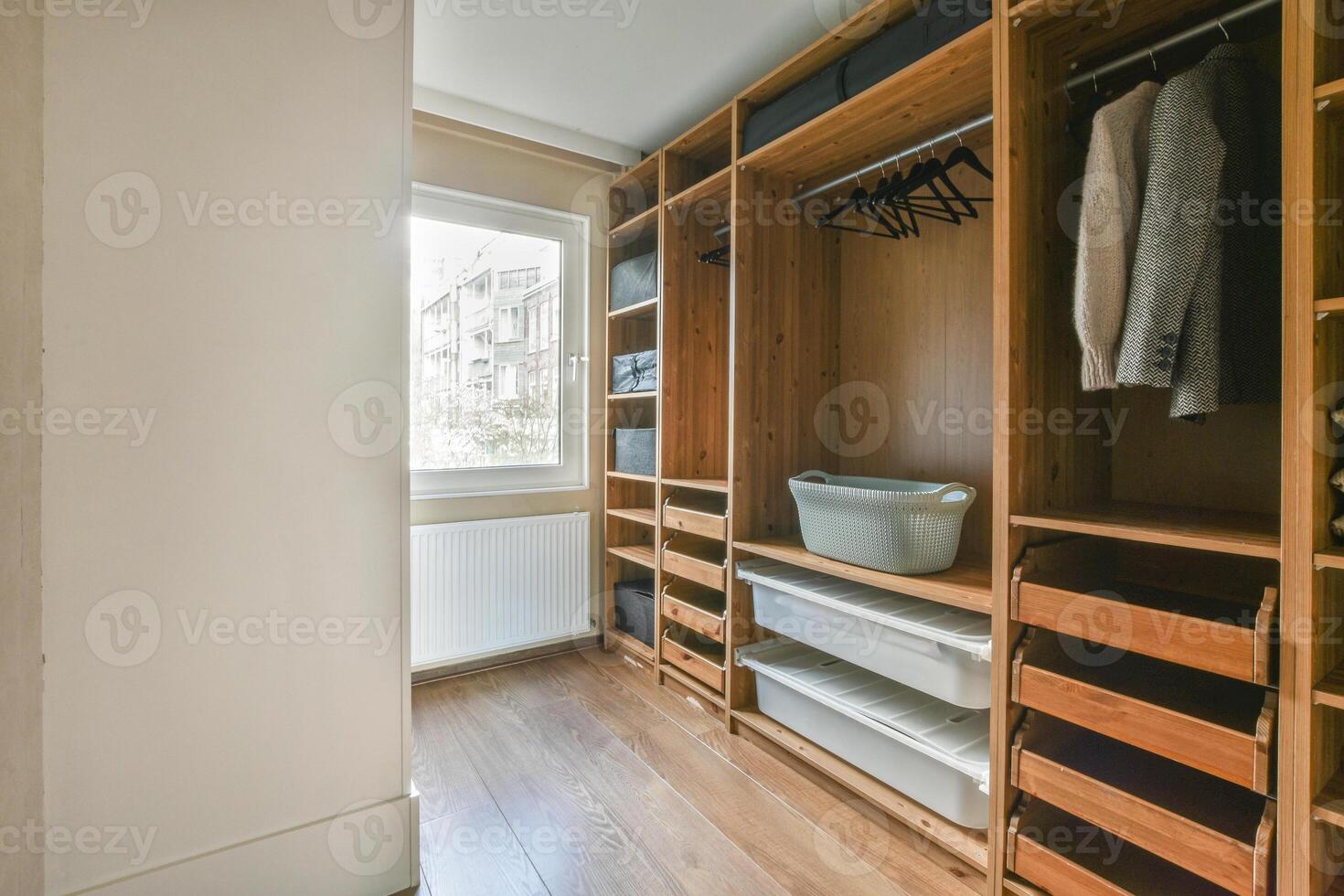 A walk in closet with wooden shelves and clothes photo