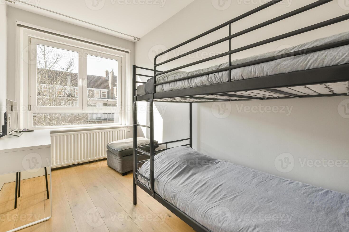 A bunk bed in a small room with a desk and window photo
