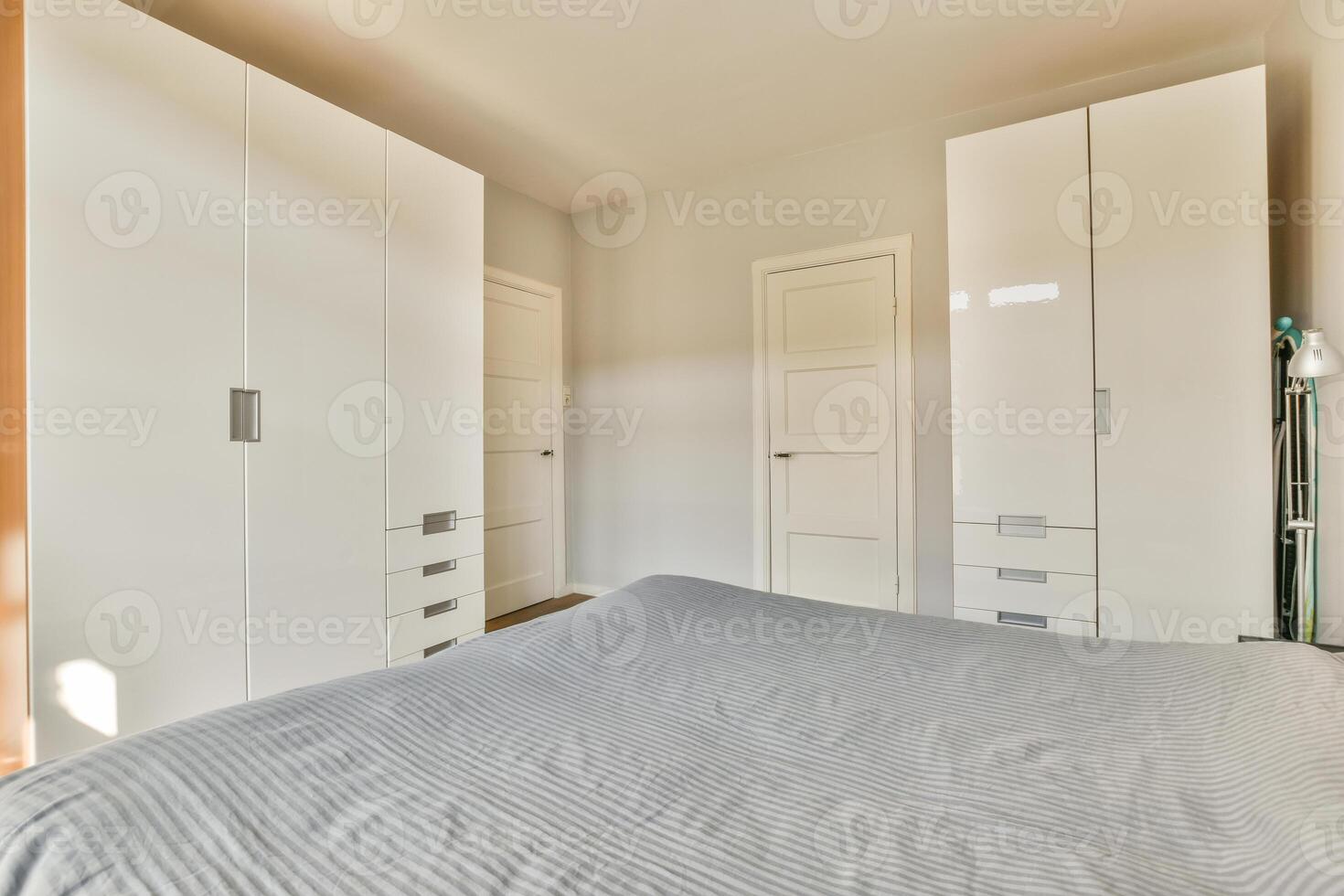 A bedroom with white cabinets and a bed photo