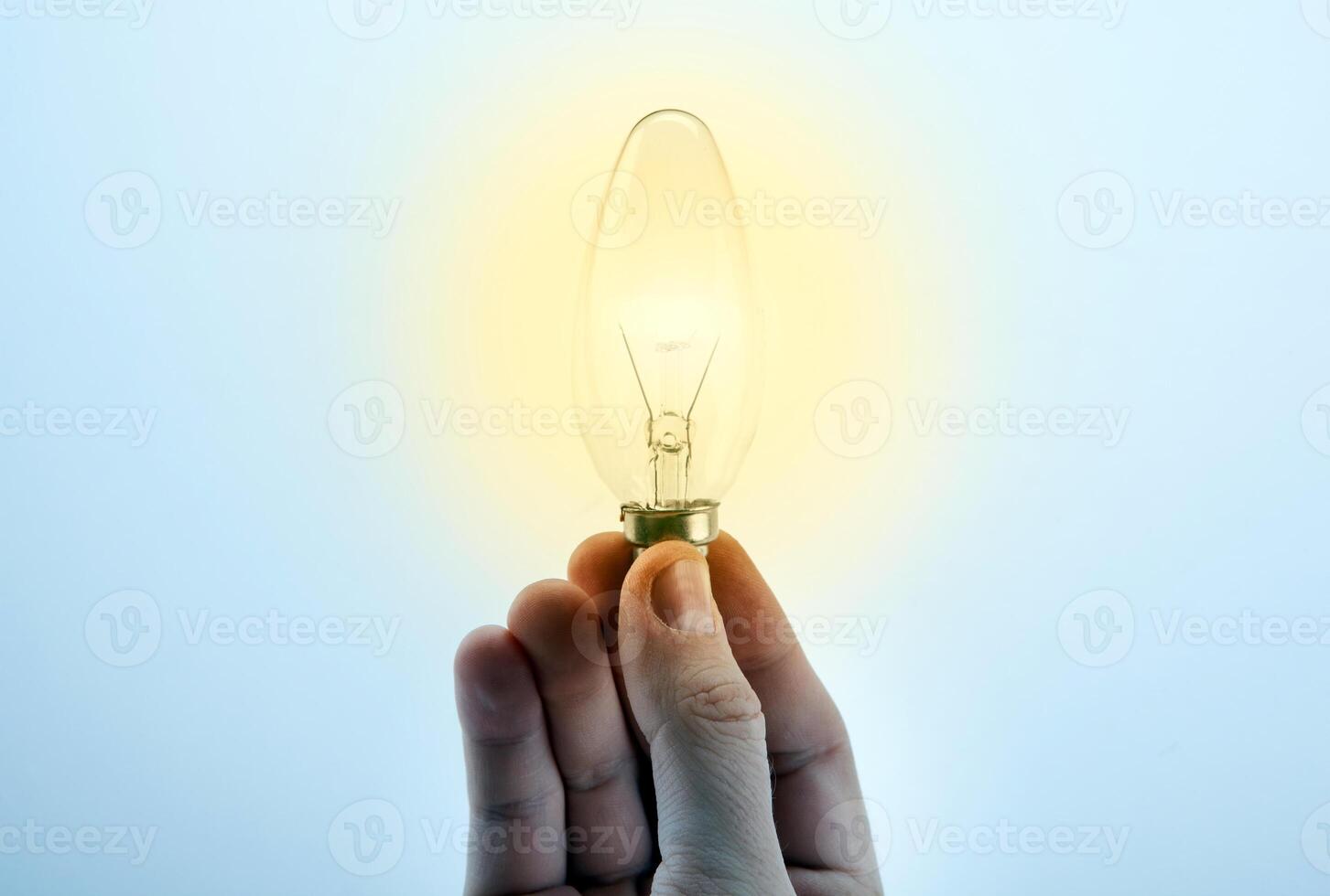 Men's hand holds a burning light bulb and the symbol of the idea photo