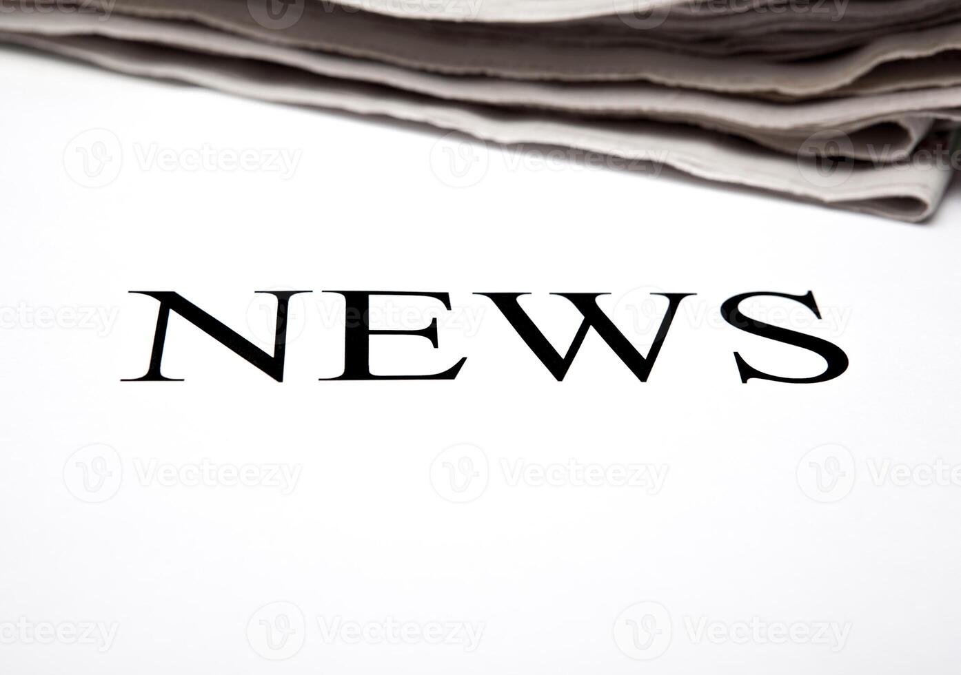the word news on the background of a stack of newspapers photo