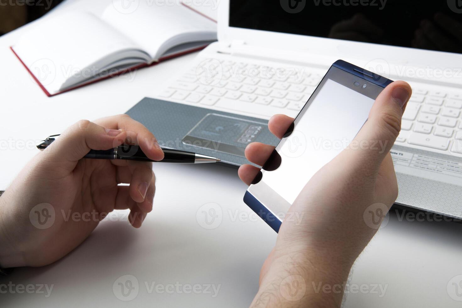 human fingers near the notebook keyboard and smartphone photo