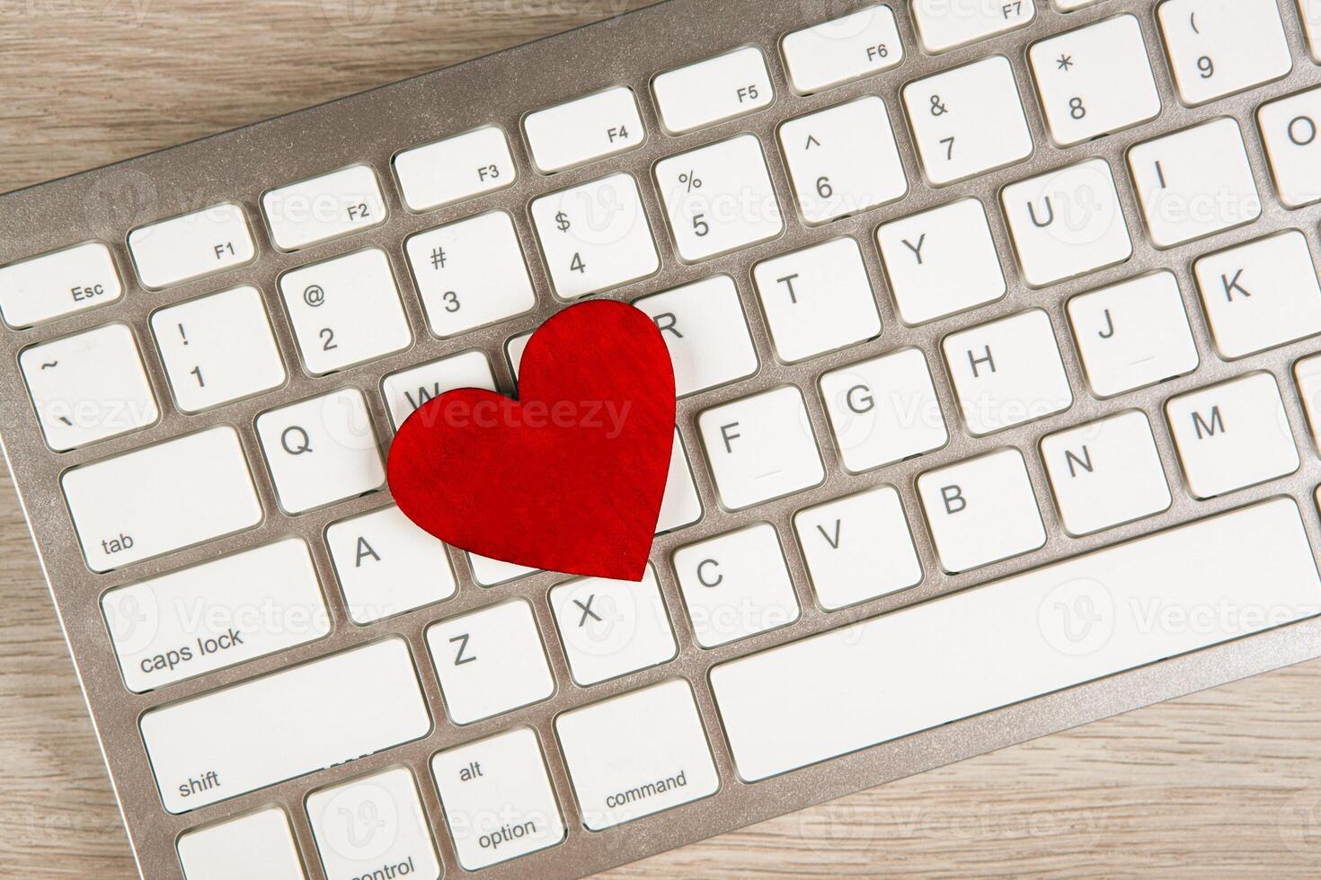 red heart on a white keyboard top view dating network concept photo