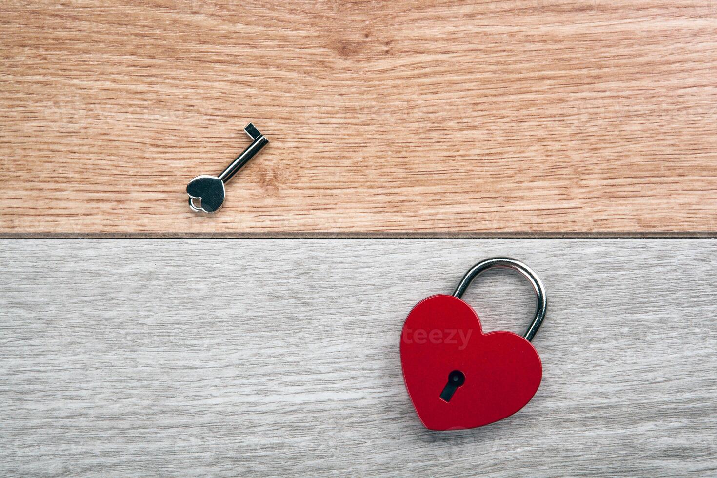 red heart shaped padlock plus a key on a wooden background photo