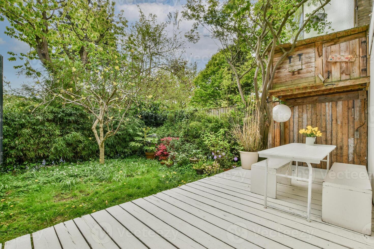 A small patio with white furniture and a wooden fence photo