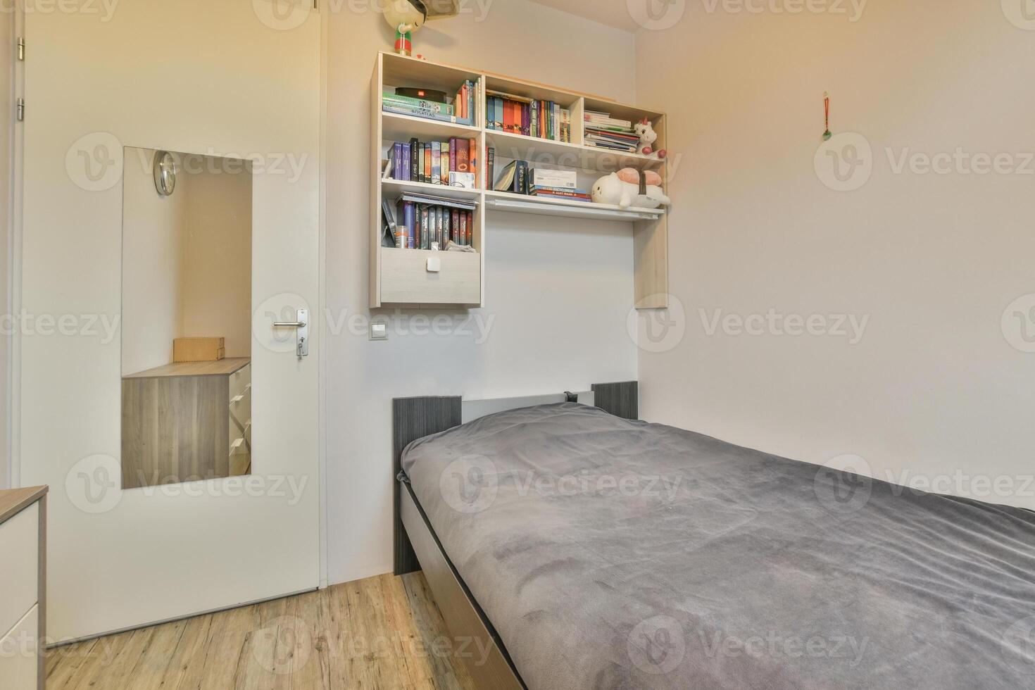 A small bedroom with a bed and a book shelf photo