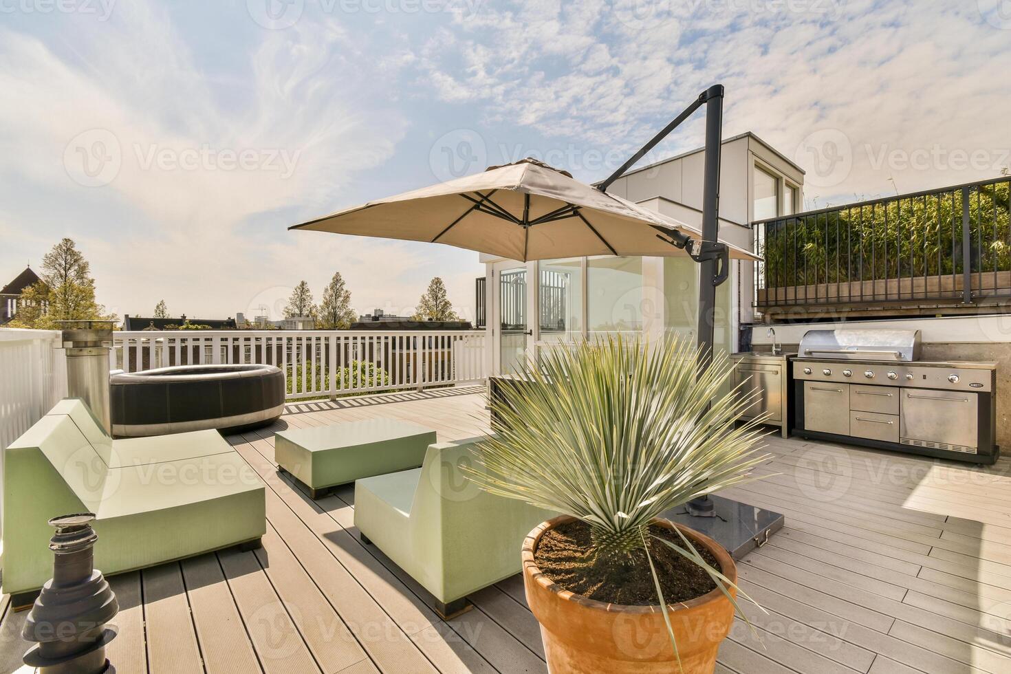 A deck with a patio umbrella and a grill photo
