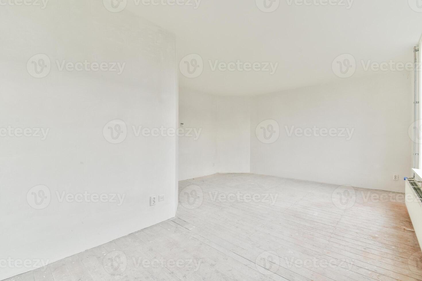A white room with a window and a wooden floor photo