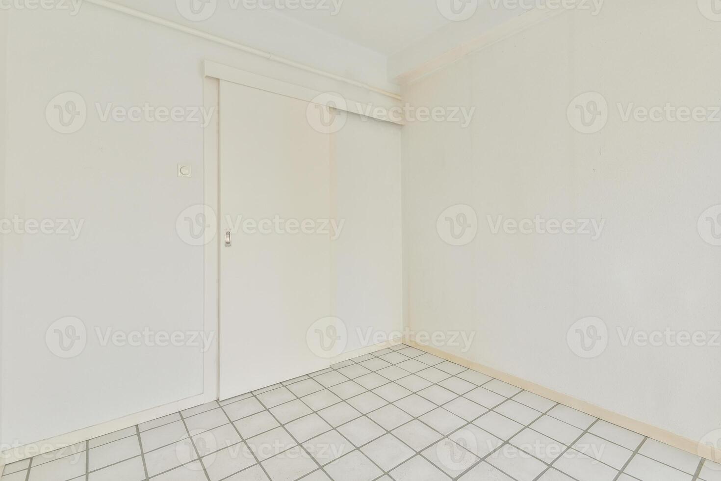 An empty room with white walls and tile floor photo