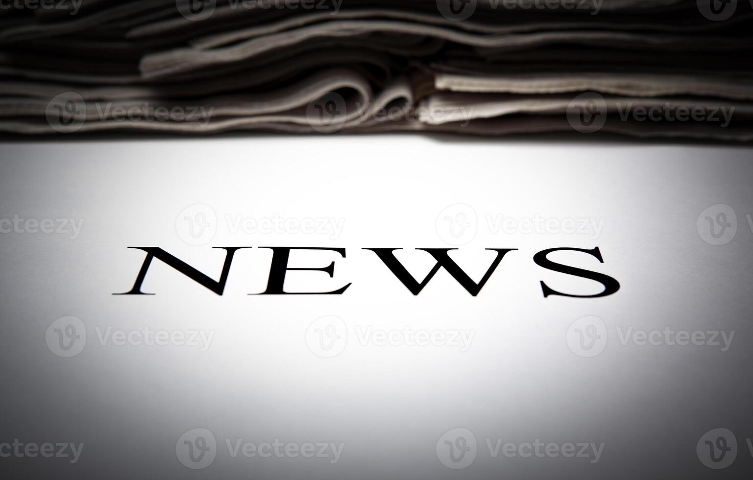 the word news on the background of a stack of newspapers photo