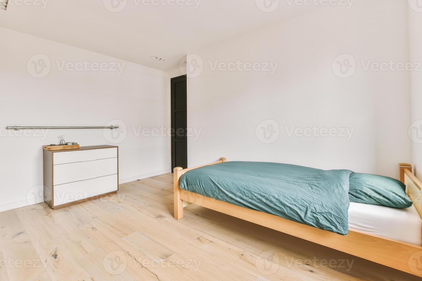 A bedroom with a bed, dresser and a white wall photo